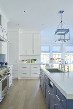 a large kitchen with white cabinets and blue counter tops, along with an island in the middle