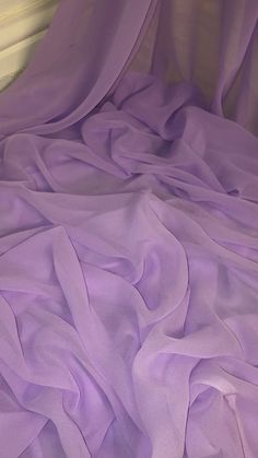 an unmade bed covered in purple sheets