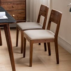 two wooden chairs sitting next to each other on top of a hard wood floored floor