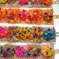 three rows of beaded bracelets with flowers and beads on them, all in different colors