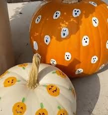 two pumpkins with faces painted on them sitting next to each other in the sand