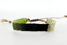 a green and black bracelet on a white surface with a string attached to the clasp