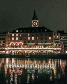 the building is lit up at night with lights reflecting in the water and buildings on both sides