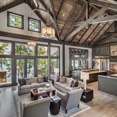 a living room filled with lots of furniture next to a stone wall and ceiling covered in windows