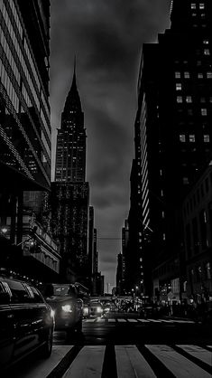 black and white photograph of cars driving down the street in new york city at night