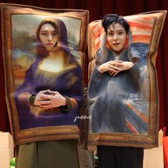 two people standing next to each other in front of paintings