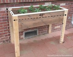 a wooden planter sitting next to a brick wall with measurements for the height and width