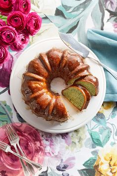 a bundt cake sitting on top of a white plate next to pink flowers and silverware