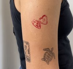 a woman's arm with tattoos on it, including a turtle and two hearts