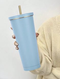 a woman holding a blue cup with a straw in it