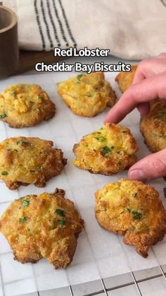 a person pointing at some food on a white tray with the words red lobster cheddar bay biscuits