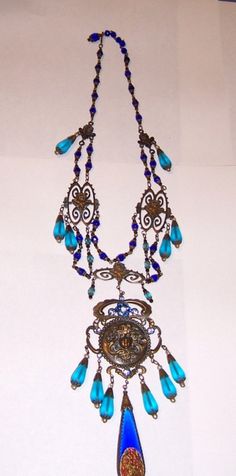 This an outstanding turquoise and cobalt blue Czechoslovakian bib necklace. The design and their attention to detail truly exemplify their craftsmanship. The necklace measures 16 in length and is stamped on the reverse side of the large medallion. This exquisite necklace is in excellent Ornate Blue Pendant Necklace, Antique Blue Jewelry With Large Pendant, Antique Blue Medallion Necklace, Blue Medallion Pendant Jewelry, Blue Medallion Jewelry With Large Pendant, Vintage Turquoise Necklace For Jewelry Making, Vintage Blue Turquoise Necklace For Jewelry Making, Victorian Blue Pendant Necklace, Blue Victorian Pendant Necklace