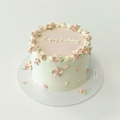 a birthday cake decorated with pink flowers and the words happy birthday on it's side