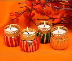 four candles are sitting on an orange surface