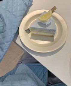 a piece of cake sitting on top of a white plate next to a blue quilt