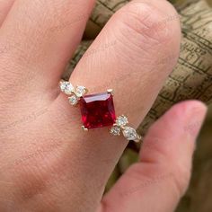 a woman's hand with a red and white diamond ring on top of it