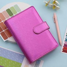 a pink wallet sitting on top of a table next to a pen and sticker