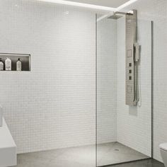 a white tiled bathroom with a glass shower door and toilet in the corner next to it