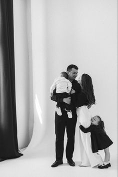 a man, woman and child standing in front of a white backdrop