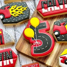 decorated cookies with cars and balloons are on a wooden board next to other cookies that have the number five