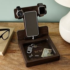 a cell phone is sitting on top of a wooden stand with eyeglasses and money