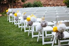 rows of white chairs with yellow and gray pom poms