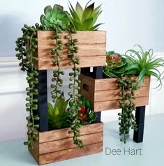 three wooden planters with succulents and plants growing out of them on top of each other