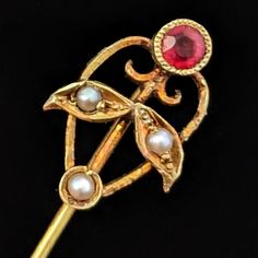 Introducing a delicate antique stick pin or lapel pin from the early 20th century that embodies the refined beauty of a bygone era. Crafted from 14k gold, this exquisite piece features a pinkish-red old-cut gemstone and luminous seed pearls arranged in a charming floral design. The intricate detailing and graceful curves of the pin highlight the exceptional craftsmanship, making it a perfect accessory for adding a touch of vintage charm to any outfit. Ideal for collectors and lovers of antique j Art Nouveau Jewelry, Seed Pearl, Pearl Gemstone, Gold Floral, Lapel Pin, Early 20th Century, Vintage Charms, Favorite Things Gift, Antique Jewelry