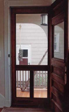 an open door leading to a porch with a lamp on the side and stairs in the background