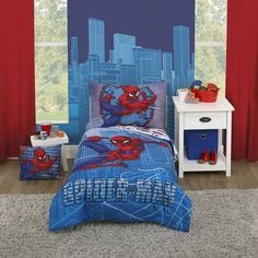 a spiderman themed bedroom with red curtains and blue bedding is pictured in front of a cityscape backdrop