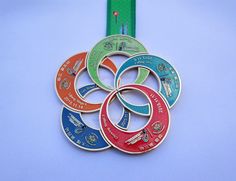 four different colored medals on a blue background with a green ribbon in the foreground