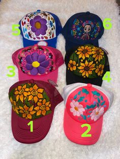 five different colored hats with flowers on them sitting on a white furnishing area