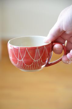 a person is holding a red and white coffee cup