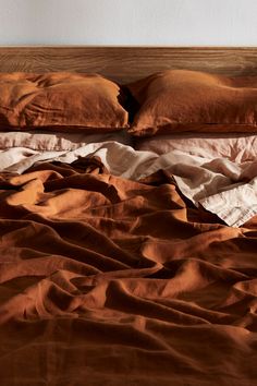 an unmade bed with brown sheets and pillows