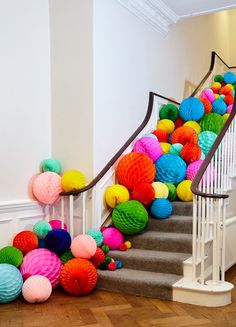 colorful paper balls are on the stairs in this hallway decorated with white banisters