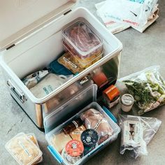 an open lunch box sitting on the ground next to other food and condiments