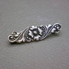 This small 800 silver brooch is an authentic Yogya  (also known as Jogya or Djokja) Yogyakarta repousse silverwork from Java Indonesia, handcrafted in 1930's. This dainty bar brooch is featuring a beautifully stylized flower ornament. A lovely piece of Asian Art Deco jewelry with lots of character! The brooch will be shipped in a gift box. The brooch measures 1 2/5 inches long by 2/5 inches wide  (3.5 cm x 1 cm)  Weight: 3.2 grams Roll-over clasp closure The brooch is hallmarked for 800 silver, Elegant Engraved Brooches For Ceremonial Occasions, Silver Art Nouveau Jewelry For Ceremonial Occasions, Art Nouveau Silver Jewelry For Ceremonial Occasions, Classic Silver Brooches With Intricate Design, Silver Art Nouveau Brooch, Silver Engraved Victorian Brooches, Ornate Silver Flower Brooches, Silver Victorian Engraved Brooch, Victorian Silver Engraved Brooch