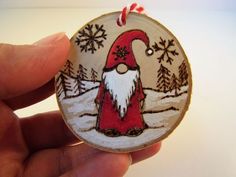 a hand holding a christmas ornament with a santa clause on it