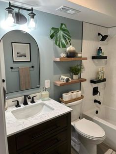 a white toilet sitting under a bathroom mirror next to a sink and bathtub in a bathroom