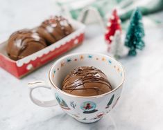 a cup filled with chocolate frosting sitting on top of a counter next to christmas decorations