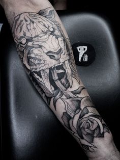 a man's arm with a tiger and rose tattoo on it