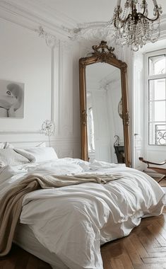 a bedroom with a bed, mirror and chandelier on the wall next to it