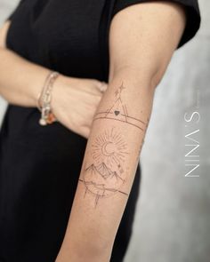 a woman's arm with a tattoo on it that has an image of a sun in the middle