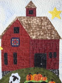 a quilted red barn with sheep and pumpkins