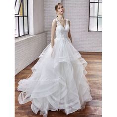 a woman in a white wedding dress standing on a wooden floor next to a window