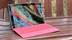 a tablet with a keyboard is sitting on a wooden bench in front of a window