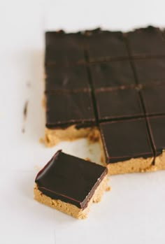 two pieces of chocolate and peanut butter bars on a white surface with one cut in half