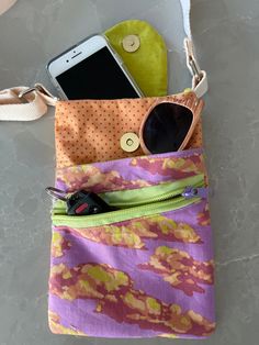 a cell phone and sunglasses are sitting in a pouch on the floor next to a purse