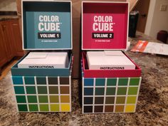 two boxes with colored cubes in them sitting on a counter