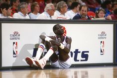 a basketball player sitting on the floor in front of a crowd